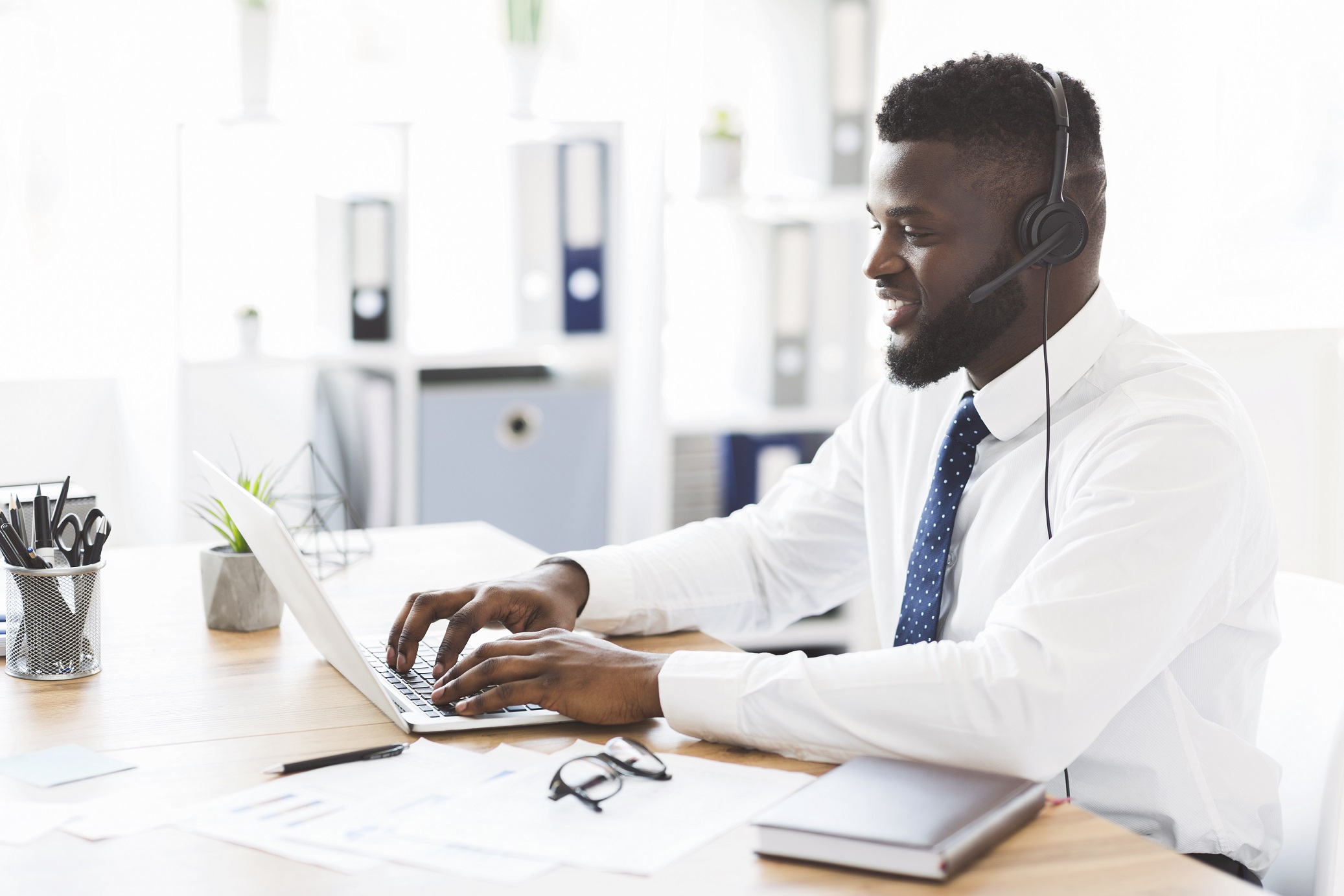 Happy office worker helping clients, using laptop Happy african american office worker helping clients, using laptop, copy space